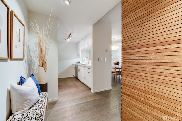 hallway with light wood finished floors, baseboards, and a sink