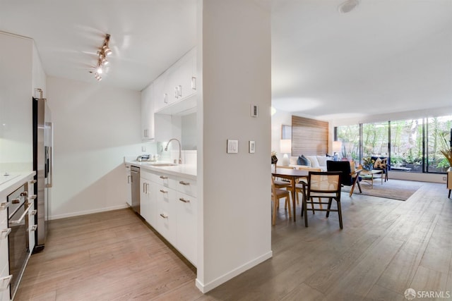 kitchen featuring light wood-type flooring, stainless steel appliances, light countertops, and open floor plan