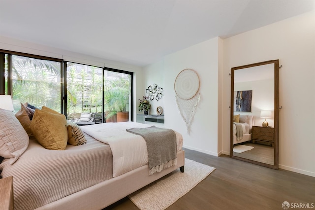 bedroom featuring access to exterior, baseboards, and wood finished floors