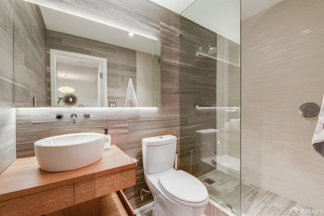 bathroom featuring toilet, vanity, walk in shower, and tile walls