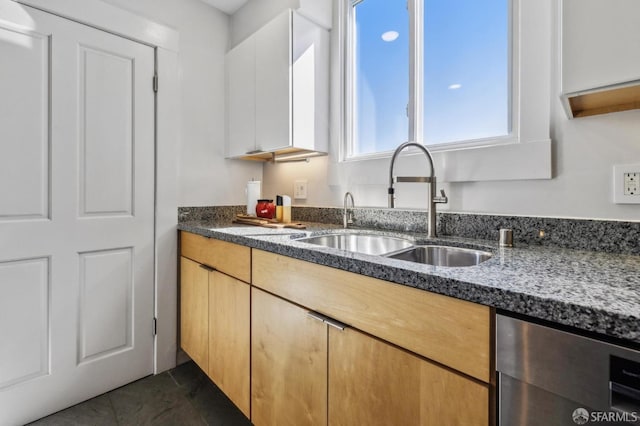 kitchen featuring dark tile patterned flooring, a sink, and dark stone countertops