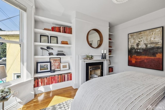 bedroom with a fireplace, multiple windows, and wood finished floors