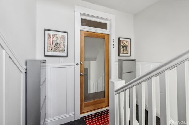 stairway with a decorative wall and a wainscoted wall