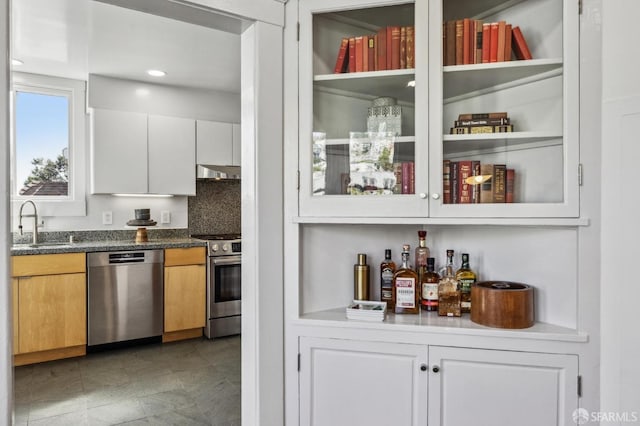 bar with tasteful backsplash, a sink, appliances with stainless steel finishes, under cabinet range hood, and recessed lighting