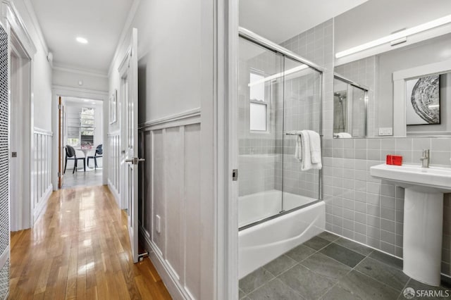 full bathroom featuring a sink, tile walls, ornamental molding, and enclosed tub / shower combo