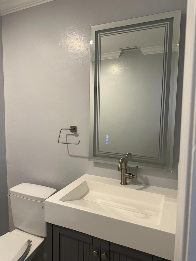 bathroom with toilet, vanity, and ornamental molding