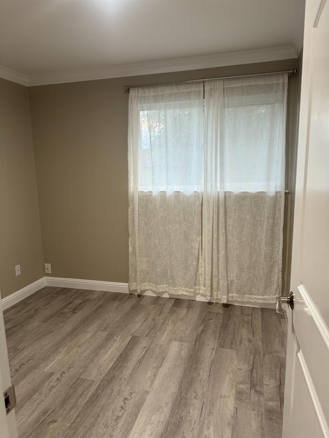 empty room with ornamental molding and hardwood / wood-style flooring