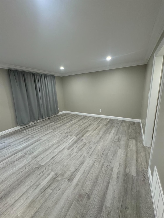 spare room featuring ornamental molding and light hardwood / wood-style flooring