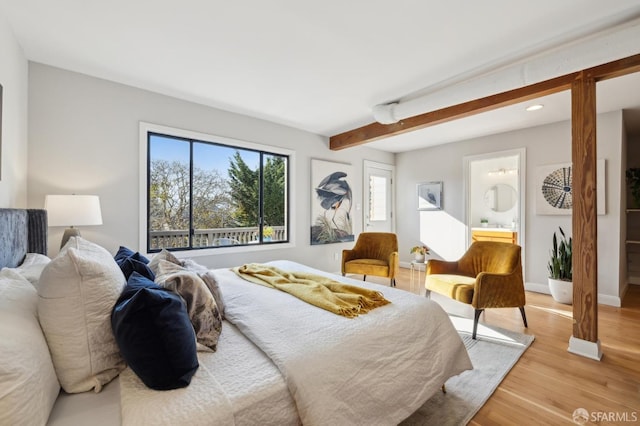 bedroom with beamed ceiling, light hardwood / wood-style floors, and ensuite bath