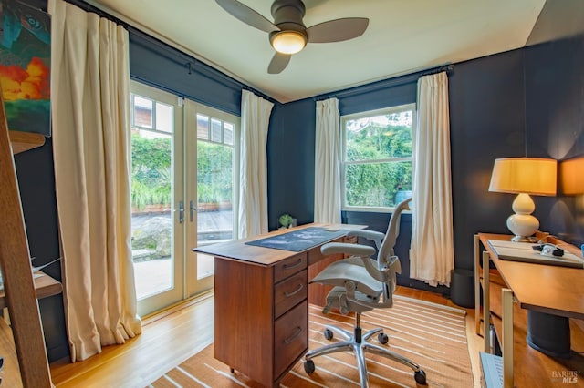 home office with a ceiling fan, light wood-style floors, and french doors