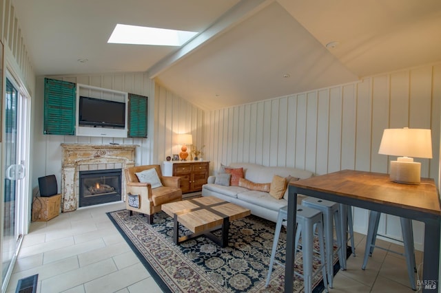 living area with vaulted ceiling with skylight, light tile patterned flooring, visible vents, and a warm lit fireplace