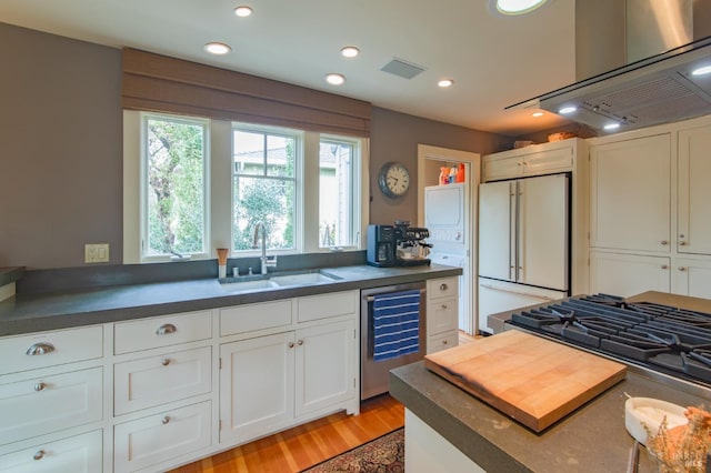 kitchen with visible vents, a sink, dark countertops, wine cooler, and high end refrigerator