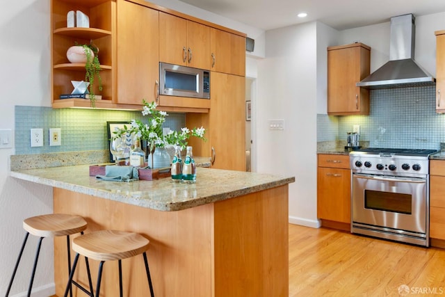 372 Baltimore Way, San Francisco, CA 94112 - kitchen with appliances with stainless steel finishes, wall chimney range hood, light wood-type flooring, a kitchen bar, and tasteful backsplash