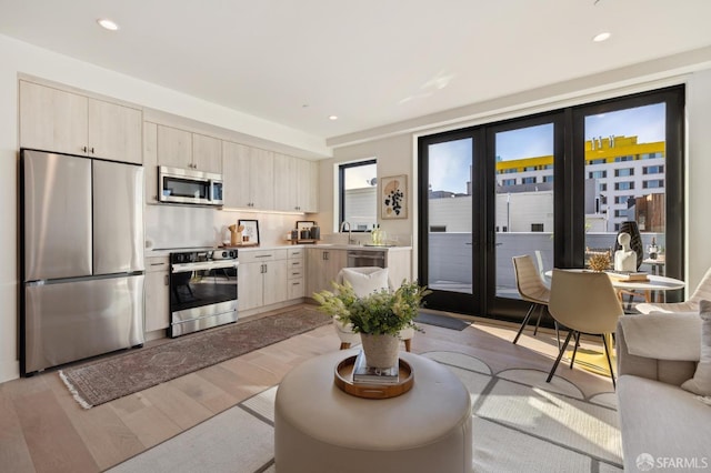 kitchen with sink, stainless steel appliances, french doors, and light wood-type flooring