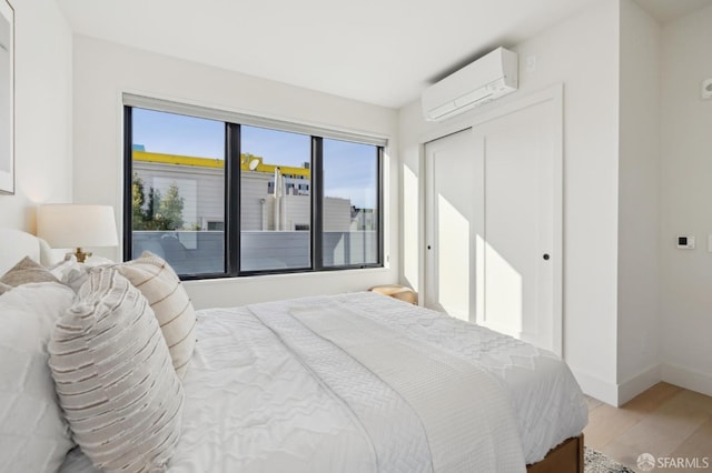 bedroom featuring an AC wall unit, a closet, and light hardwood / wood-style floors