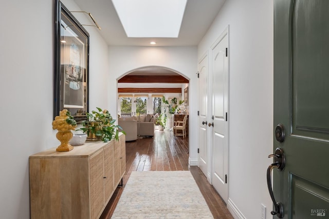 foyer entrance featuring arched walkways, recessed lighting, dark wood-style flooring, a skylight, and beam ceiling