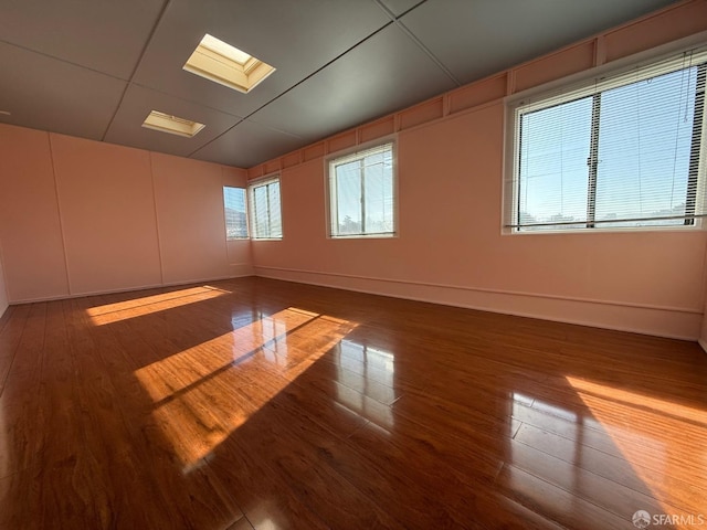 unfurnished room with hardwood / wood-style flooring and a skylight