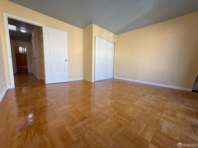 unfurnished bedroom featuring light parquet floors, lofted ceiling, and a closet