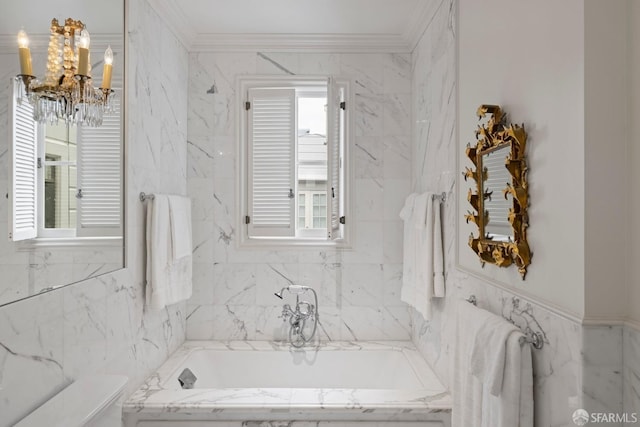 bathroom featuring ornamental molding, a chandelier, and tiled tub