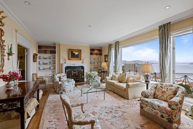 living room with a high end fireplace, ornamental molding, built in features, and light wood-type flooring