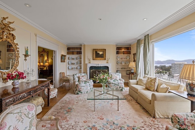 living room featuring ornamental molding, a high end fireplace, a mountain view, and built in features