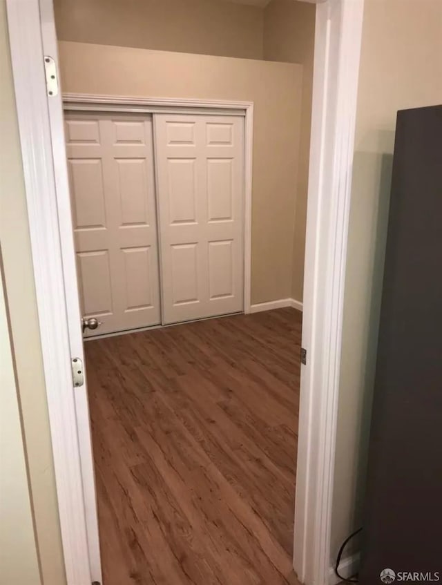 hall with baseboards and wood finished floors