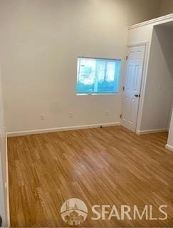 spare room featuring baseboards and wood finished floors