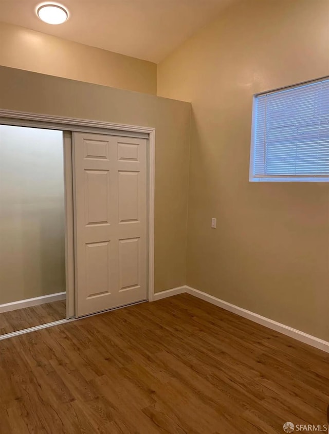 unfurnished bedroom featuring a closet, baseboards, and wood finished floors