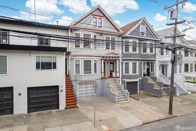multi unit property featuring concrete driveway, stairs, a garage, and stucco siding