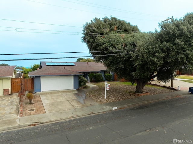 ranch-style house featuring a garage and solar panels