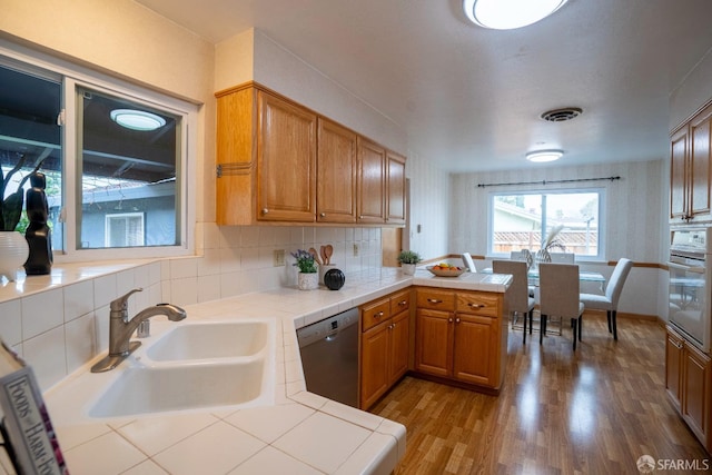 kitchen featuring sink, tile countertops, stainless steel dishwasher, kitchen peninsula, and oven