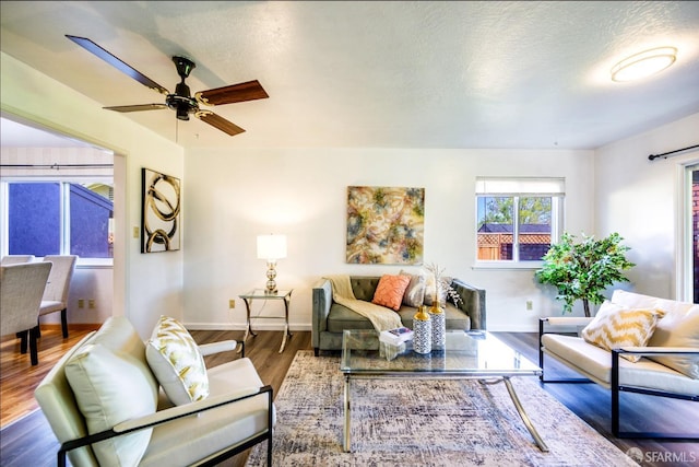 living room with ceiling fan, dark wood-type flooring, and a textured ceiling