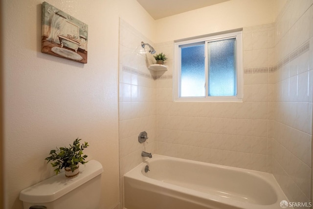 bathroom featuring tiled shower / bath combo and toilet