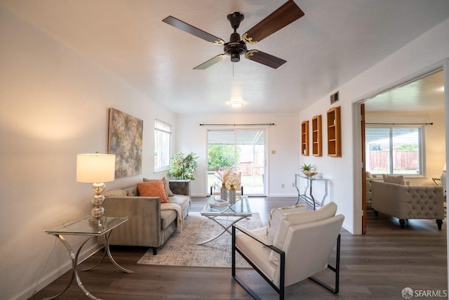 living room featuring dark wood-type flooring, ceiling fan, and a healthy amount of sunlight