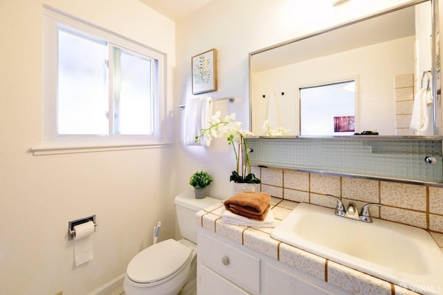 bathroom with vanity, decorative backsplash, and toilet