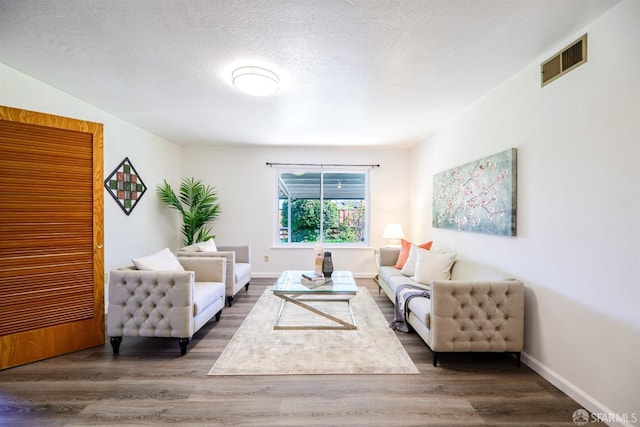 living room with a textured ceiling and dark hardwood / wood-style flooring