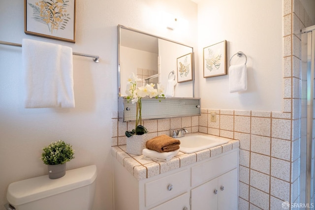 bathroom with vanity, toilet, and tile walls