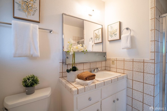 bathroom featuring vanity, toilet, and tile walls