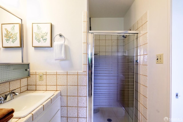 bathroom with a shower with door, vanity, and tile walls