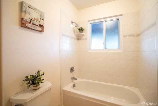 bathroom featuring tiled shower / bath and toilet