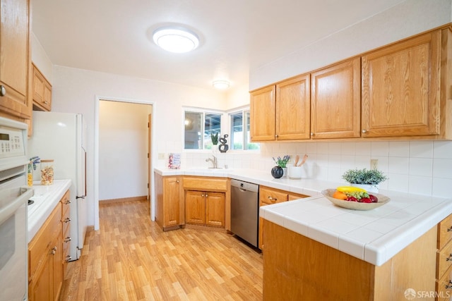 kitchen with tasteful backsplash, tile counters, white appliances, and light hardwood / wood-style floors