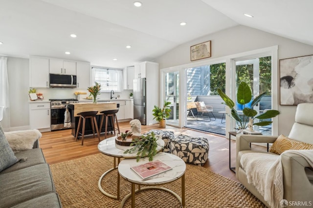 living room with recessed lighting, light wood-style flooring, and lofted ceiling