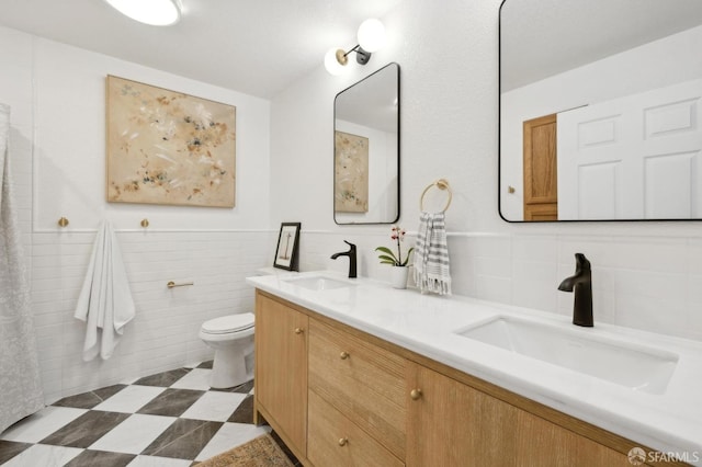 bathroom with vanity, toilet, and tile walls