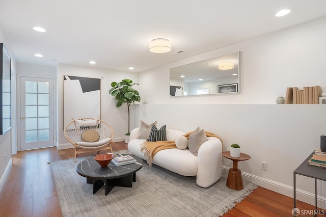 living area with recessed lighting, wood finished floors, and baseboards