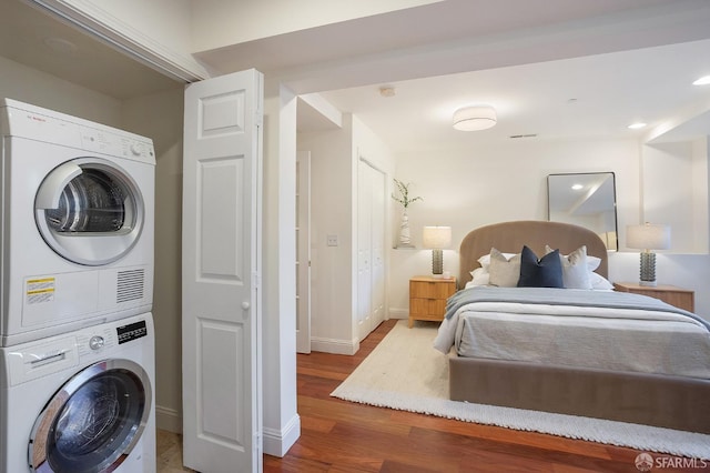 interior space with baseboards, wood finished floors, and stacked washer and clothes dryer