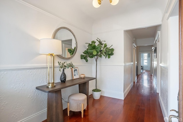 corridor with a textured wall, wood finished floors, and baseboards