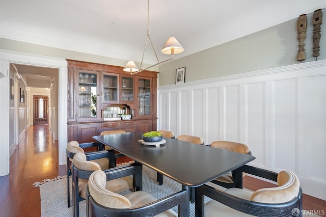 dining room with wainscoting, a decorative wall, and wood finished floors