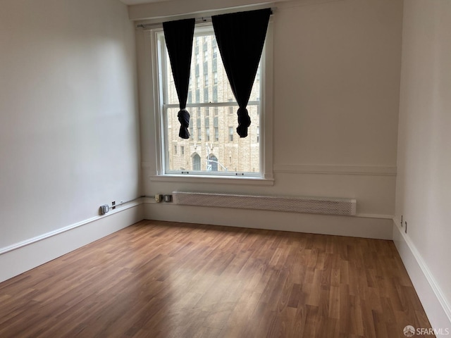 empty room with hardwood / wood-style floors and radiator heating unit