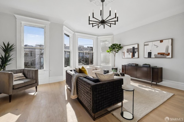 living room with ornamental molding, a healthy amount of sunlight, a notable chandelier, and light wood-type flooring