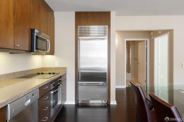 kitchen with light stone countertops, appliances with stainless steel finishes, and dark hardwood / wood-style flooring